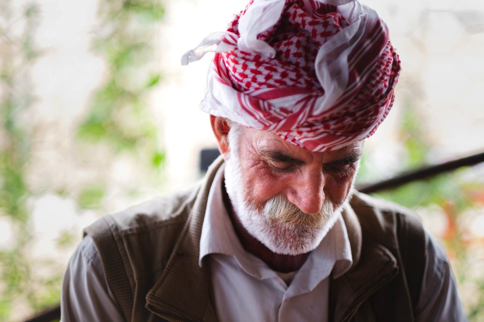Views in June of 2019 of an Ezidi man in Sardashte Camp for displaced Ezidis rolling a cigarette with tobacco grown nearby atop Shingal mountain 05
