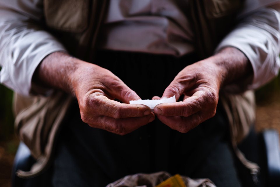 Views in June of 2019 of an Ezidi man in Sardashte Camp for displaced Ezidis rolling a cigarette with tobacco grown nearby atop Shingal mountain 31
