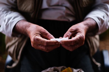Views in June of 2019 of an Ezidi man in Sardashte Camp for displaced Ezidis rolling a cigarette with tobacco grown nearby atop Shingal mountain 31