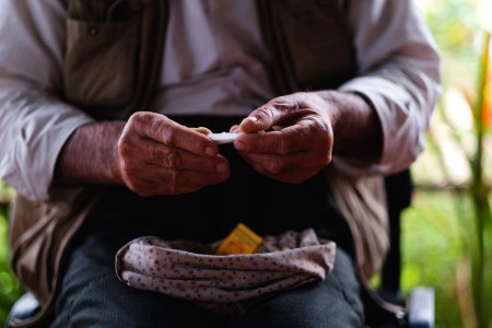 Views in June of 2019 of an Ezidi man in Sardashte Camp for displaced Ezidis rolling a cigarette with tobacco grown nearby atop Shingal mountain 19