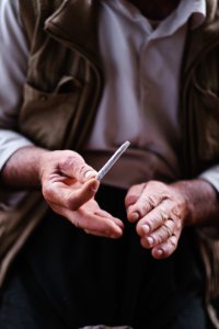 Views in June of 2019 of an Ezidi man in Sardashte Camp for displaced Ezidis rolling a cigarette with tobacco grown nearby atop Shingal mountain 41