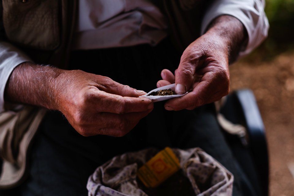 Views in June of 2019 of an Ezidi man in Sardashte Camp for displaced Ezidis rolling a cigarette with tobacco grown nearby atop Shingal mountain 28