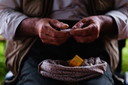 Views in June of 2019 of an Ezidi man in Sardashte Camp for displaced Ezidis rolling a cigarette with tobacco grown nearby atop Shingal mountain 17