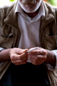 Views in June of 2019 of an Ezidi man in Sardashte Camp for displaced Ezidis rolling a cigarette with tobacco grown nearby atop Shingal mountain 39