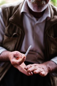 Views in June of 2019 of an Ezidi man in Sardashte Camp for displaced Ezidis rolling a cigarette with tobacco grown nearby atop Shingal mountain 42
