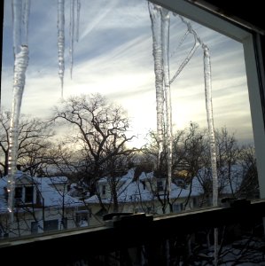 View from window with icicles hanging from gutter with houses in winter photo