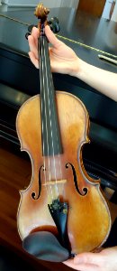 Violin held in hands sunlit angle photo