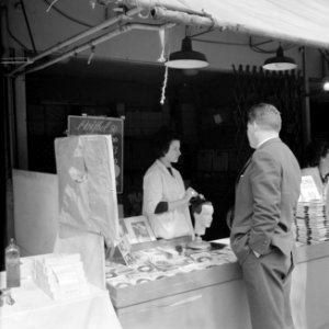 Verkoopster demonstreert het gebruik van een haaraccessoire op een kunsthoofd, Bestanddeelnr 254-0349