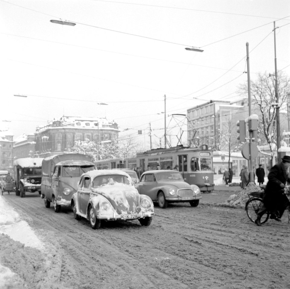 Verkeer op de Karlsplatz in de sneeuw met vooraan een Volkswagen Kever, Bestanddeelnr 254-3717