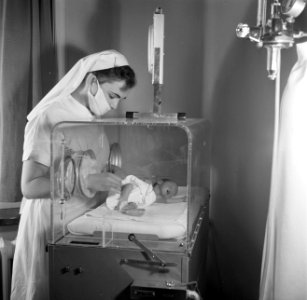 Verpleegster bij te vroeg geboren baby in een couveuse, vermoedelijk in het Sint, Bestanddeelnr 254-2526