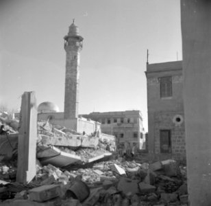 Verwoest gebouw met op de achtergrond de minaret van een moskee, Bestanddeelnr 255-0083