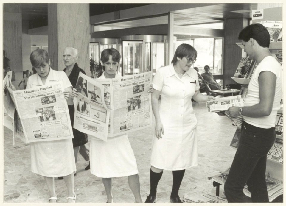 Verpleegkundigen in de hal van ziekenhuis de Mariastichting. In het Haarlems Dagblad lezen zij de aankondiging van de sluiting van het ziekenhuuis