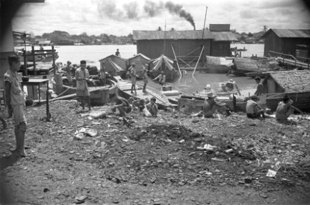 Verwoest bankgebouw Langs de rivier liggen prauwen afgemeerd. Puin aan de oever, Bestanddeelnr 123-4-5