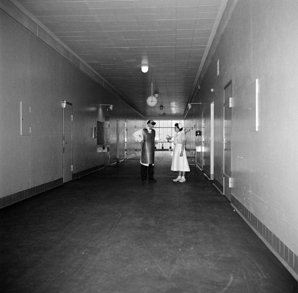 Verpleegster en een radiodiagnostisch laborant in gesprek in een gang van het zi, Bestanddeelnr 252-9132
