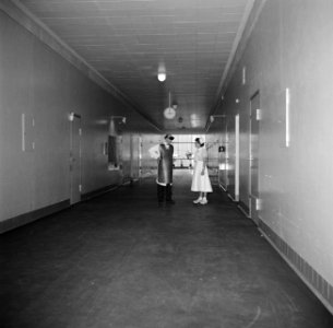 Verpleegster en een radiodiagnostisch laborant in gesprek in een gang van het zi, Bestanddeelnr 252-9132