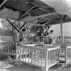 Verzorgsters en een peuter in een box bij de kinderopvang van kibboets Kiwath Br, Bestanddeelnr 255-0567 photo