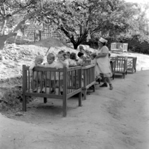 Verzorgster en peuters in boxen bij de kinderopvang van kibboets Kiwath Brenner, Bestanddeelnr 255-0566