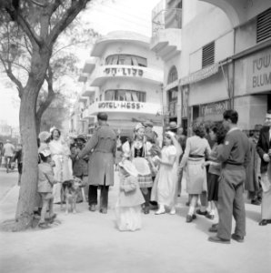 Verklede kinderen samen met volwassenen op straat bij hotel Hess in Tel Aviv bi…, Bestanddeelnr 255-1312