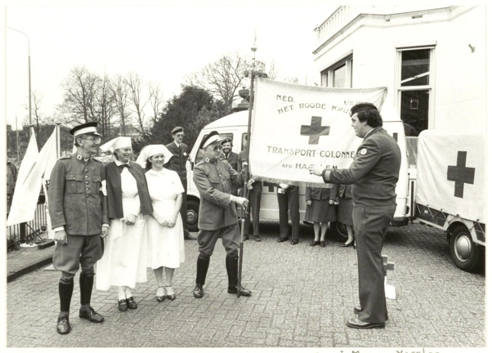 Viering van het 75-jarig bestaan van het Rode Kruis, afdeling Haarlem. Foto De in historische uniformen gestoken leden van korps overhandigen aan de commandant dr. J.M. van Yzerloo het gerestaureerde 