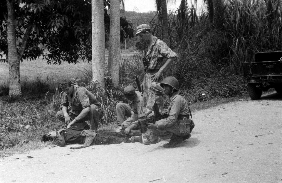 Vier KNIL-militairen bij een gesneuvelde of gewondeRepublikeinse strijder langs, Bestanddeelnr 5361