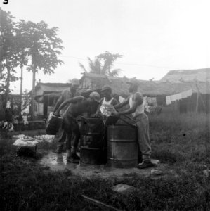 Vier mannen bezig met oliedrums met water en bakken, Bestanddeelnr 8025