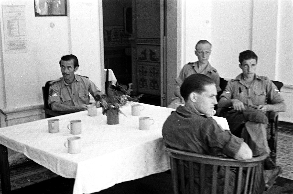 Vier militairen zitten om een tafel waarop mokken staan, Bestanddeelnr 6270
