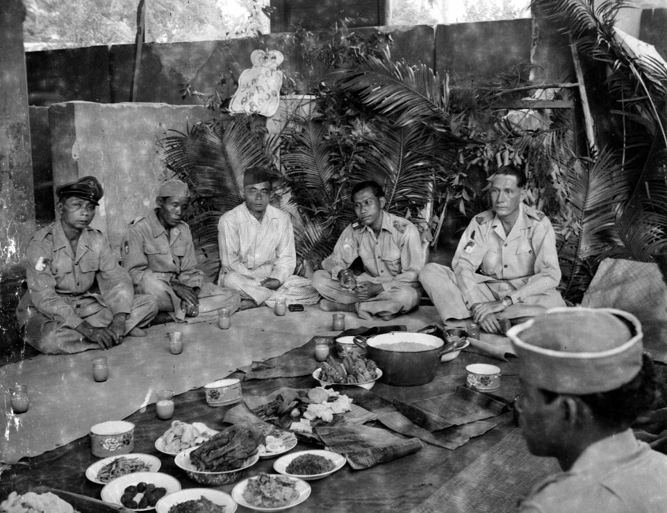 Vier militairen in lotuszit met een dorpshoofd tijdens een selamatan, Bestanddeelnr 8194