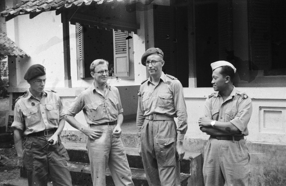 Vier mannen, waarvan drie militairen staan voor een koloniaal gebouw, Bestanddeelnr 465-1-2