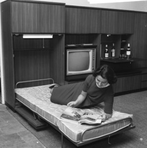 Vrouw liggend op het uitklapbare bed van een wandmeubel, Bestanddeelnr 918-4189