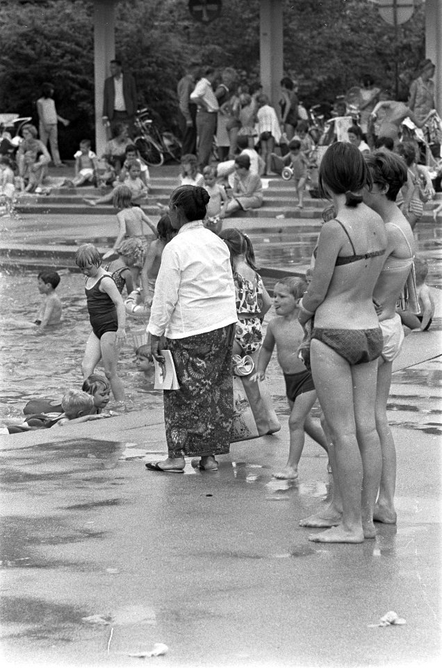 Vrouw in sarong en twee vrouwen in bikini kijken naar de kinderen in de speelvij, Bestanddeelnr 920-4848