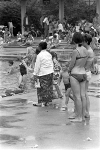 Vrouw in sarong en twee vrouwen in bikini kijken naar de kinderen in de speelvij, Bestanddeelnr 920-4848