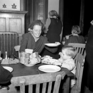 Vrouw en kind aan eettafel met bord met stapel boterhammen, Bestanddeelnr 255-9496