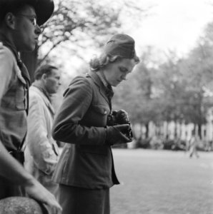 Vrouw in uniform bekijkt fototoestel, Bestanddeelnr 900-8915