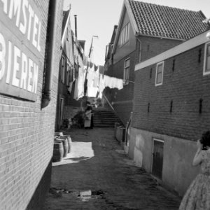 Vrouw in klederdracht bij de was die op straat hangt op de voorgrond staan hout, Bestanddeelnr 254-3986