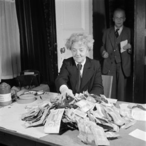 Vrouw achter een tafel met een grote hoeveelheid bankbiljetten, Bestanddeelnr 900-7201