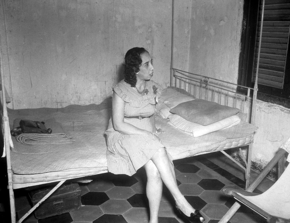 Vrouw (prostituée) in Europese kleding zit op een ledikant, Bestanddeelnr 13849