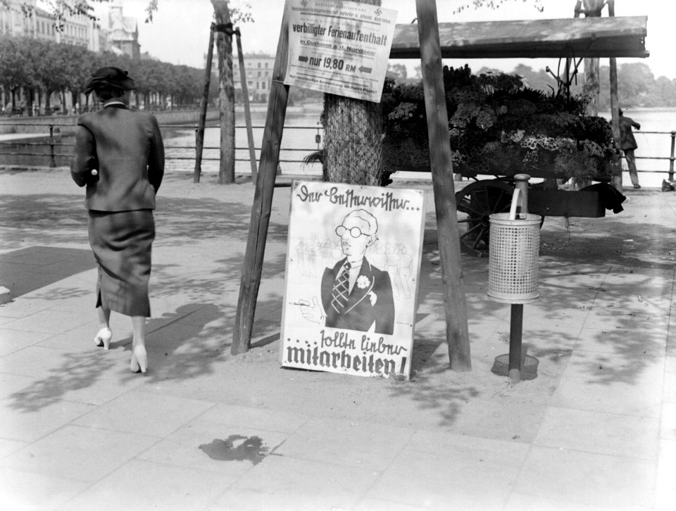 Vrouw bij posters met daarachter een bloemenstalletje, Bestanddeelnr 190-0255
