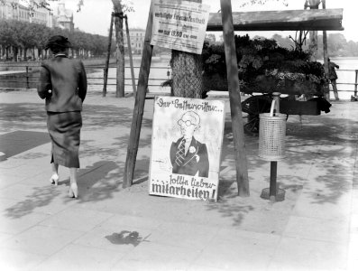 Vrouw bij posters met daarachter een bloemenstalletje, Bestanddeelnr 190-0255 photo