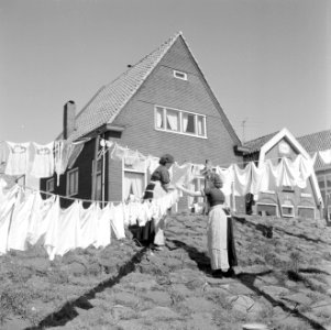 Vrouwen in klederdracht zijn in Volendam bezig met de was die op straat hangt te, Bestanddeelnr 254-3842