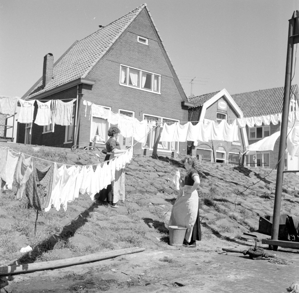 Vrouwen in klederdracht zijn in Volendam bezig met de was die op straat hangt te, Bestanddeelnr 254-3841