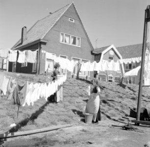 Vrouwen in klederdracht zijn in Volendam bezig met de was die op straat hangt te, Bestanddeelnr 254-3841