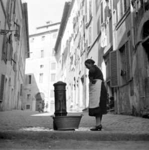 Vrouw met een zinken teil bij een waterpomp in een straatje, Bestanddeelnr 254-5538