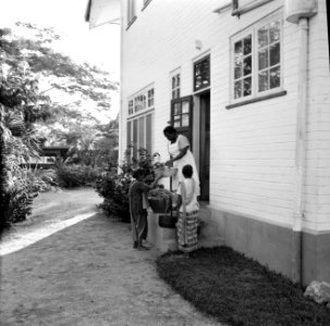 Vrouw met groentenverkoopsters aan de deur, waarschijnlijk in Paramaribo, Bestanddeelnr 252-2188