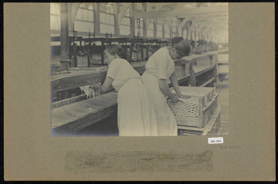 Vrouwen pakken kaarsen van de band en knippen de lonten op maat, Bestanddeelnr 256-1561