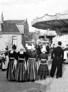 Vrouwen, man en meisjes, allen in klederdracht, kijken naar zweefmolen, Bestanddeelnr 190-1080