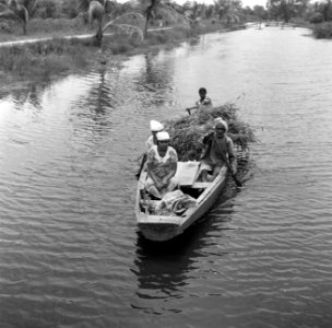 Vrouwen en mannen in een boot op een kanaal in Nickerie, Bestanddeelnr 252-5541