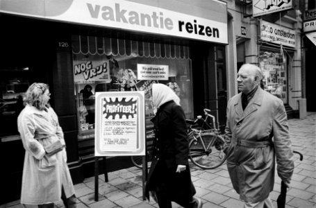 Voorbijgangers bij de etalage van van een reisbureau met uitnodigende reclametek, Bestanddeelnr 930-9145
