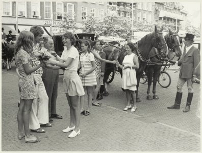 Voorbijgangers krijgen op de Grote Markt bloemen aangeboden t.g.v. het 50-jarig bestaan van de Bloemisten-winkeliersvereniging. NL-HlmNHA 54012042