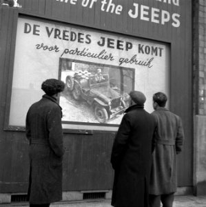 Voorbijgangers bekijken een poster met de tekst De Vredes Jeep Komt, Bestanddeelnr 901-2397