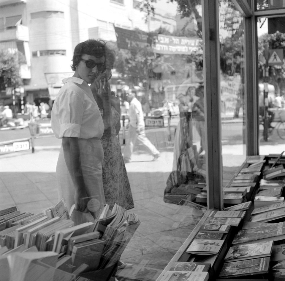 Voorbijgangers kijken geïnteresseerd in de etalage van een boekwinkel, Bestanddeelnr 255-1855
